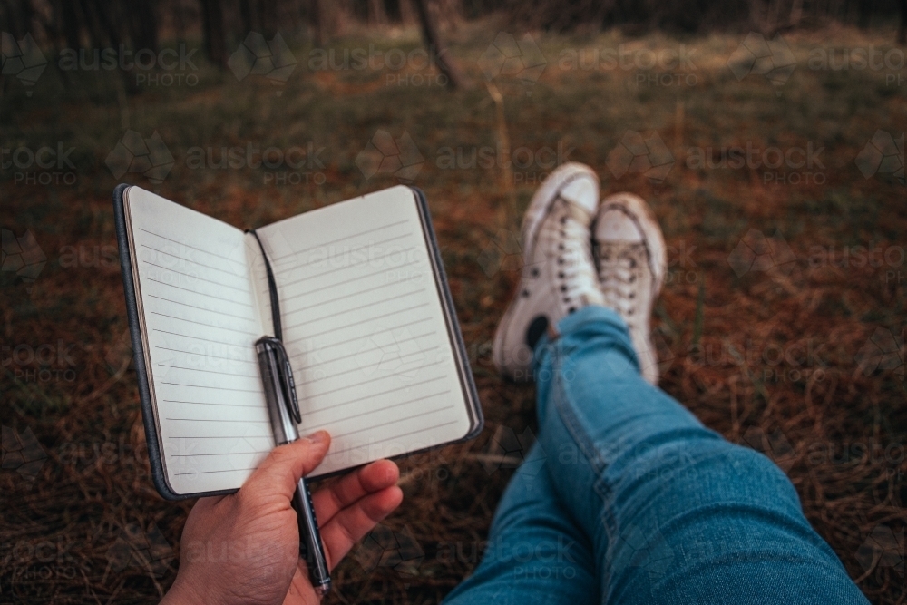 Writing in an Empty Journal while sitting in a forest. - Australian Stock Image