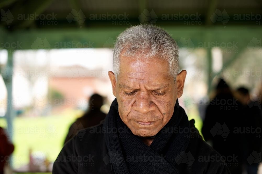 Wurundjeri Elder in Shelter Looking Down with Sad Expression - Australian Stock Image
