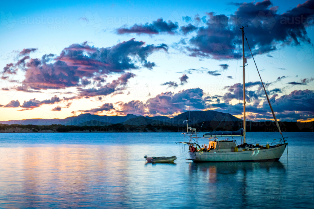 Yacht anchored in calm waters at sunset near Cooktown. - Australian Stock Image
