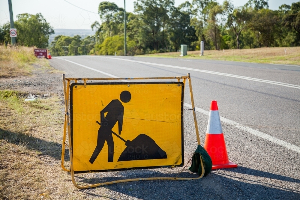 Yellow digging road work signs on road - Australian Stock Image