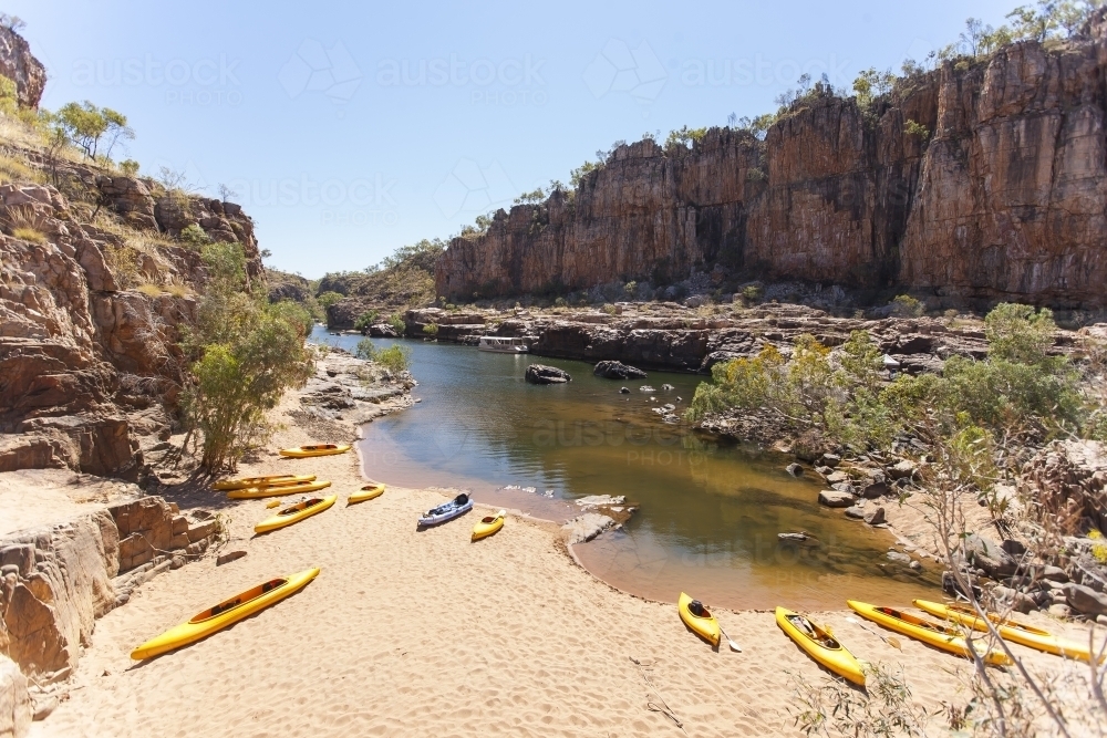 Yellow kayaks on beach in remote gorge - Australian Stock Image