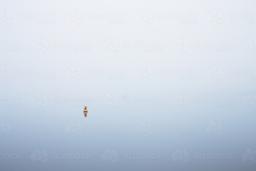 yellow marker buoy on foggy river - Australian Stock Image