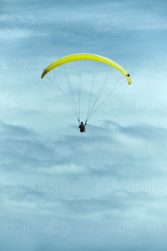 Yellow paraglider in a cloudy and moody sky - Australian Stock Image