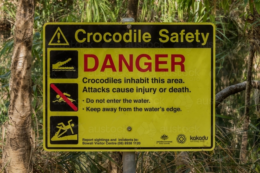 Yellow, red and black sign warning about danger of crocodiles in the water - Australian Stock Image
