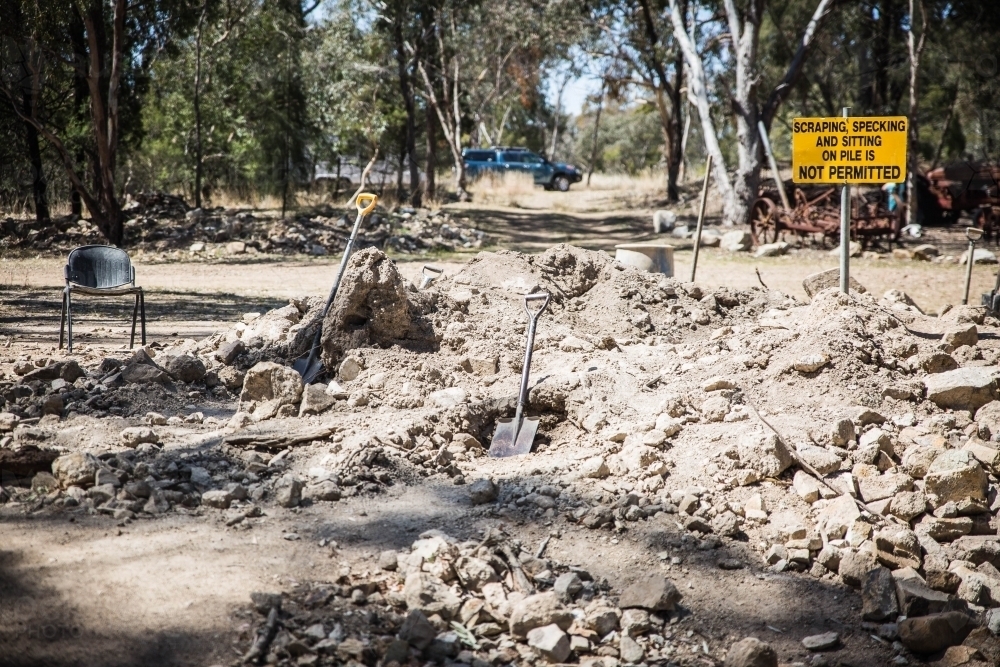 Yellow sign in pile of rocks and dirt with shovels - Australian Stock Image