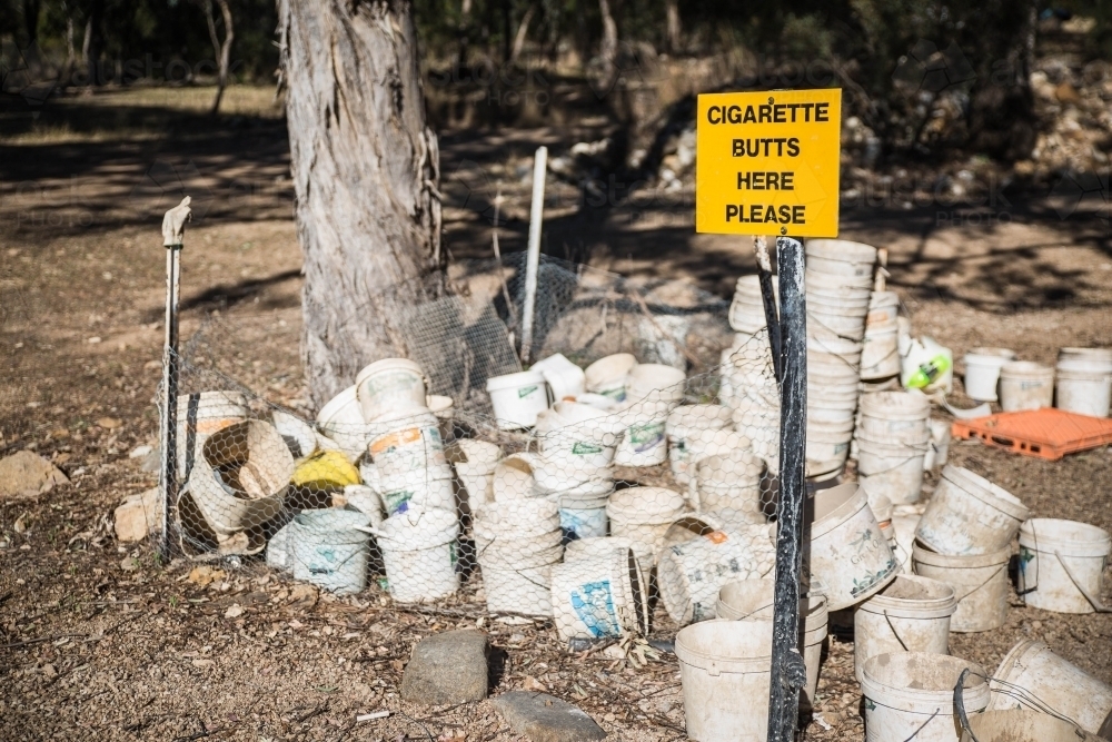 Yellow smoking sign on fence with buckets - Australian Stock Image