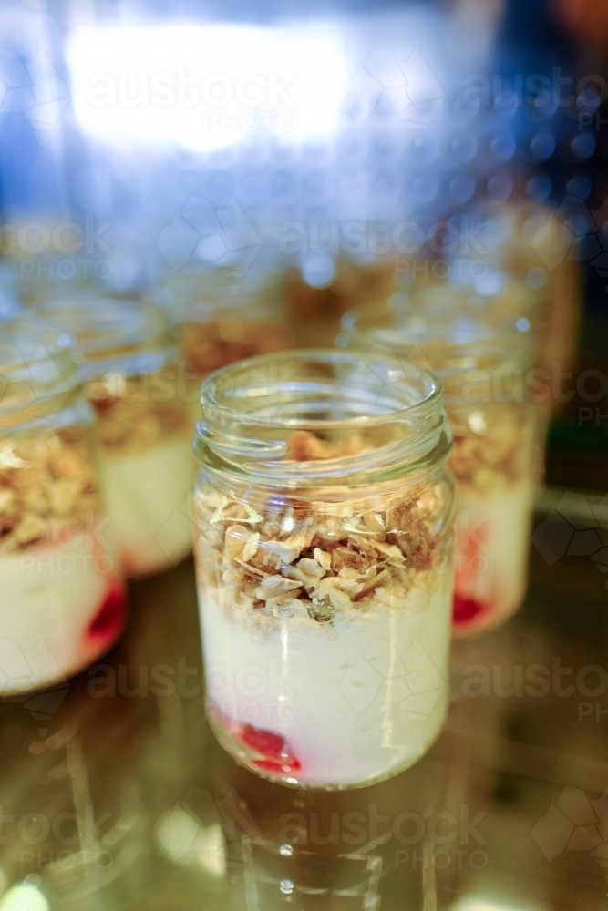 Yoghurt and granola muesli in jars at a breakfast buffet - Australian Stock Image