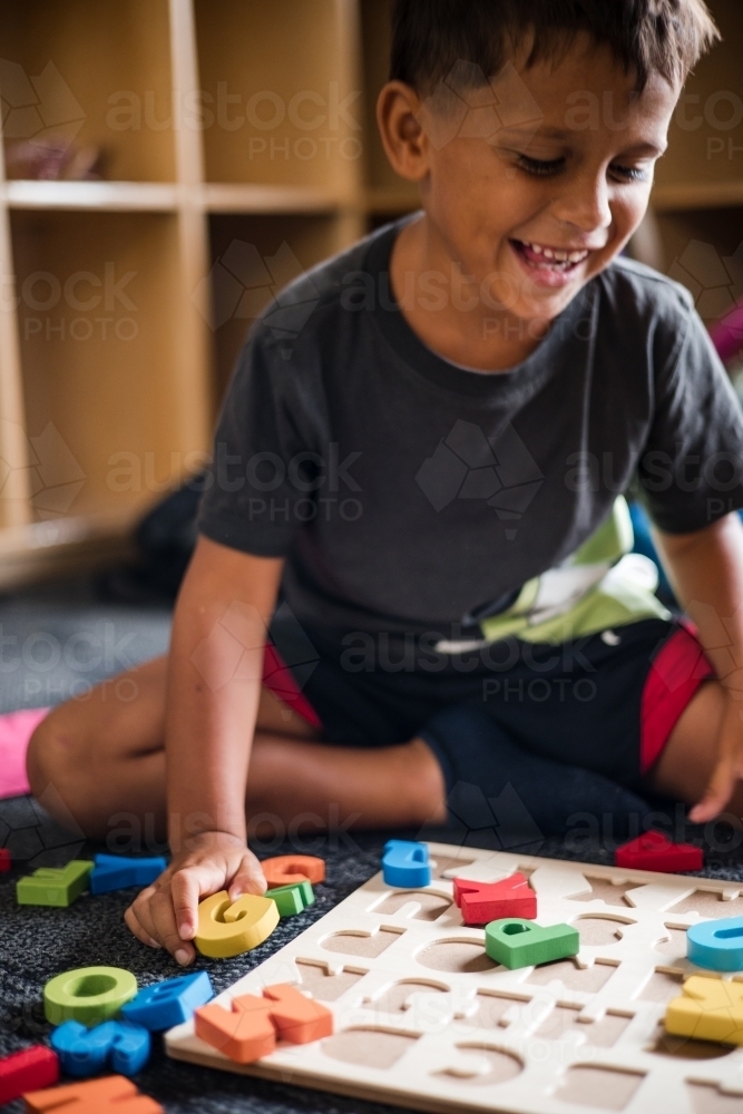 Young Aboriginal boy doing a letter puzzle - Australian Stock Image