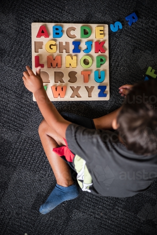 Young Aboriginal boy doing a letter puzzle - Australian Stock Image
