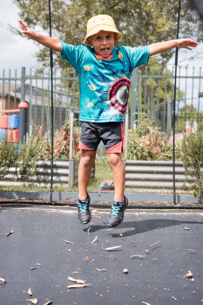 Young Aboriginal boy jumping in schoolyard - Australian Stock Image