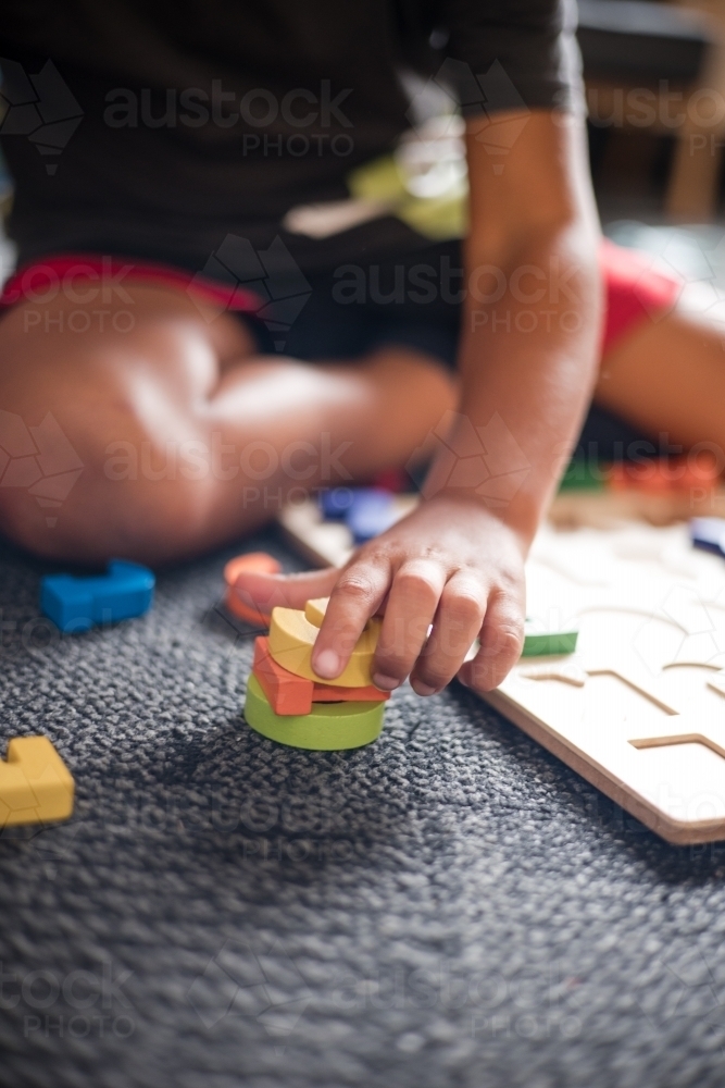 Young Aboriginal boy playing with alphabet letter puzzle pieces - Australian Stock Image