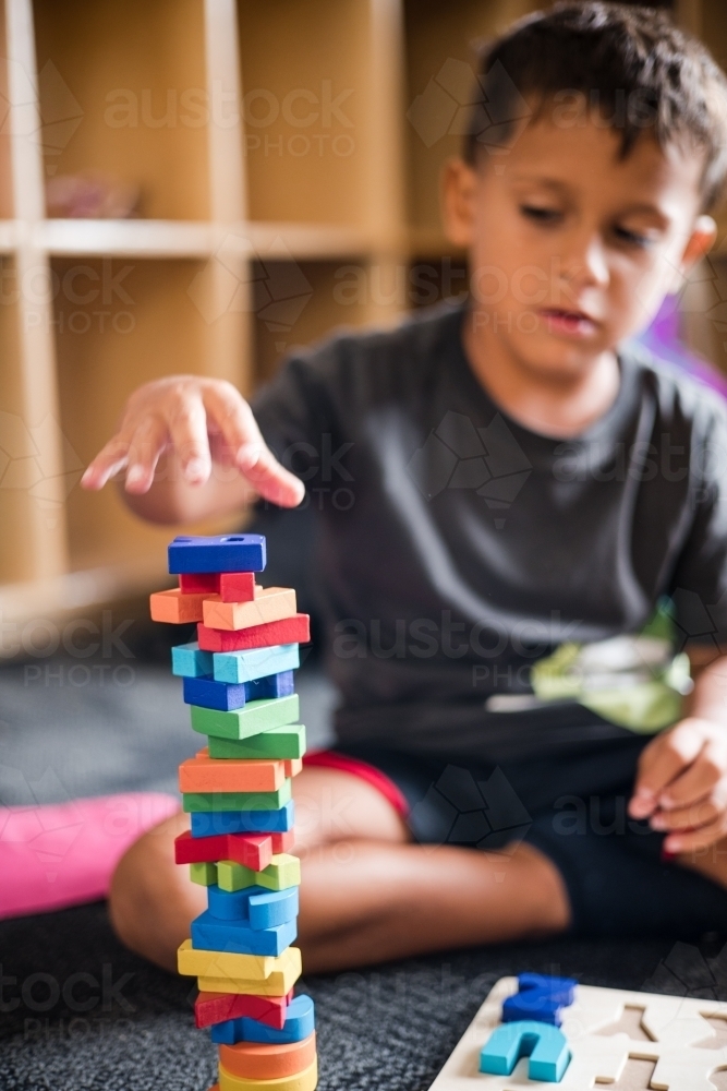 Young Aboriginal boy playing with alphabet letter puzzle pieces - Australian Stock Image