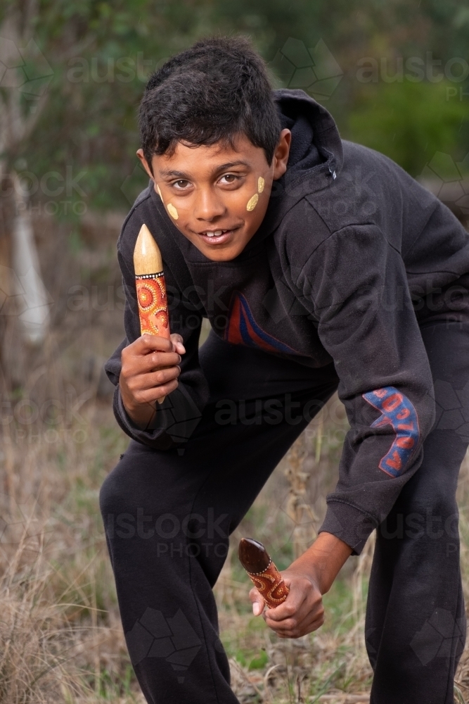 Young Aboriginal Boy with clapstick instrument - Australian Stock Image
