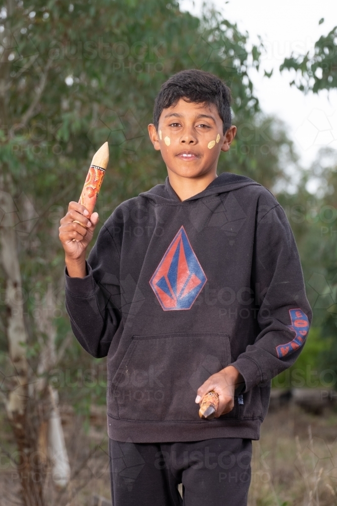 Young Aboriginal Boy with clapstick instrument - Australian Stock Image