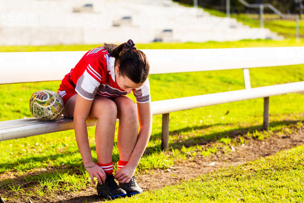 Young aboriginal footy player tying up laces on shoes before game - Australian Stock Image