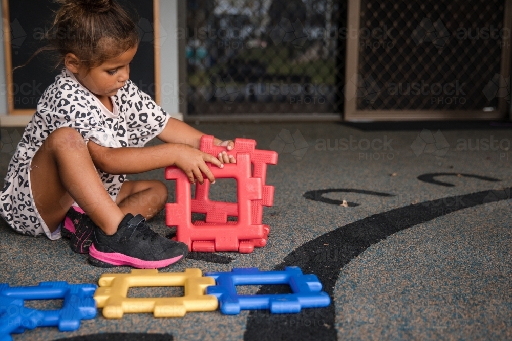 Young Aboriginal girl playing at preschool with plastic toy - Australian Stock Image