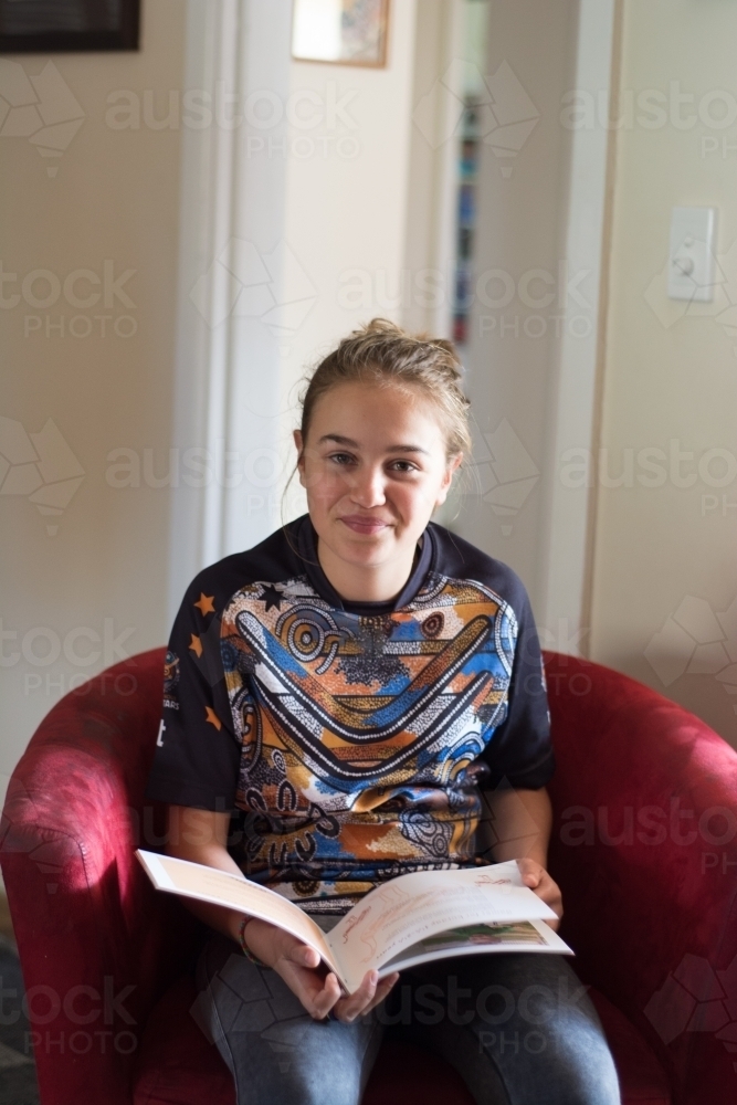 young aboriginal girl smiling reading a book - Australian Stock Image