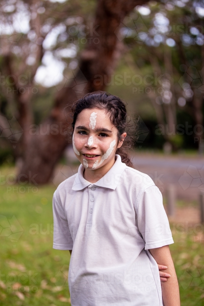 Young Aboriginal girl wearing white face paint smiling - Australian Stock Image