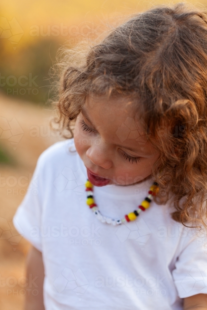 Young aboriginal girl with curly brown hair looking down - Australian Stock Image