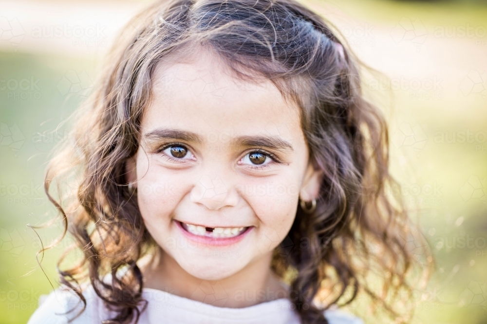 Young aboriginal girl with missing tooth and curly hair smiling - Australian Stock Image