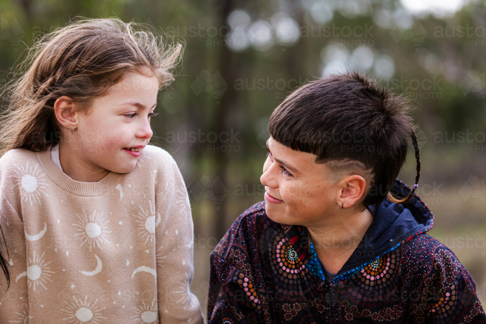 Young aboriginal kids smiling at each other outside - Australian Stock Image