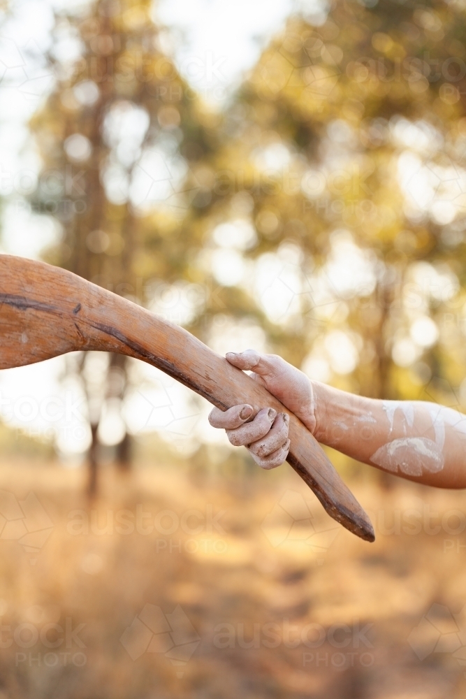 Young aboriginal man pointing with traditional stick in bushland telling stories of Australia - Australian Stock Image