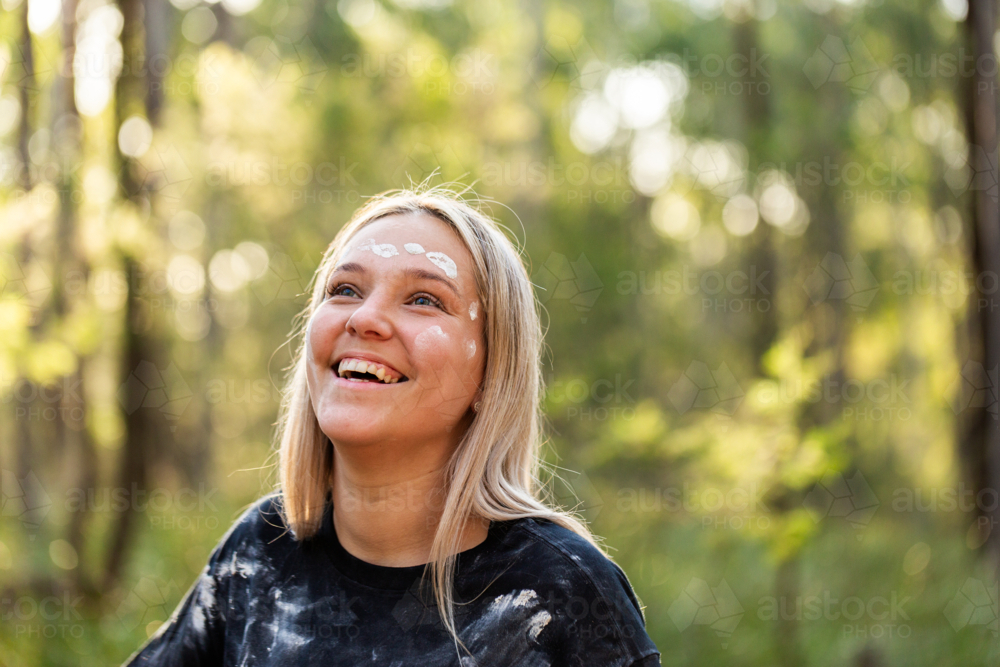 Young aboriginal woman in her twenties laughing in green bushland - Australian Stock Image