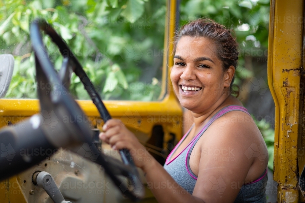 young aboriginal woman laughing looking in old wreck of car - Australian Stock Image