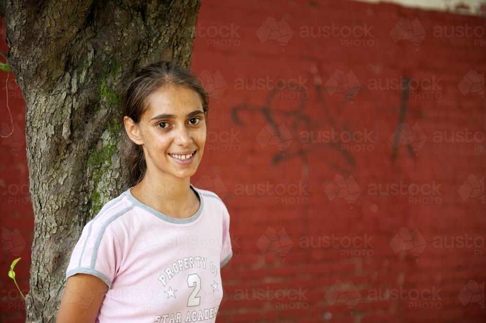 Young Aboriginal Woman with Red Wall in Background - Australian Stock Image