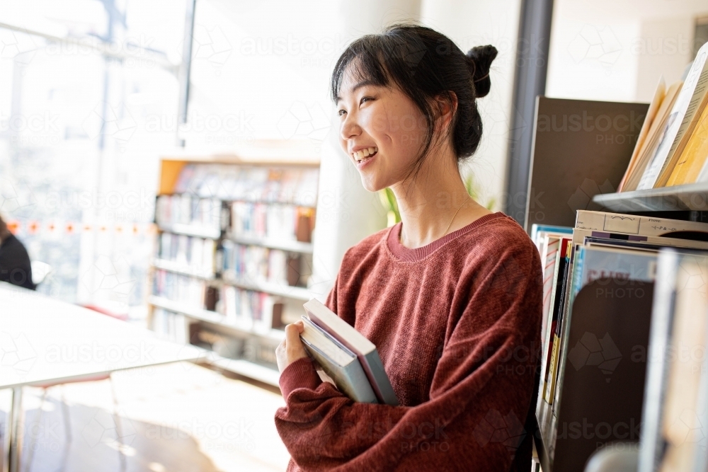 Young adult asian female student at the library - Australian Stock Image