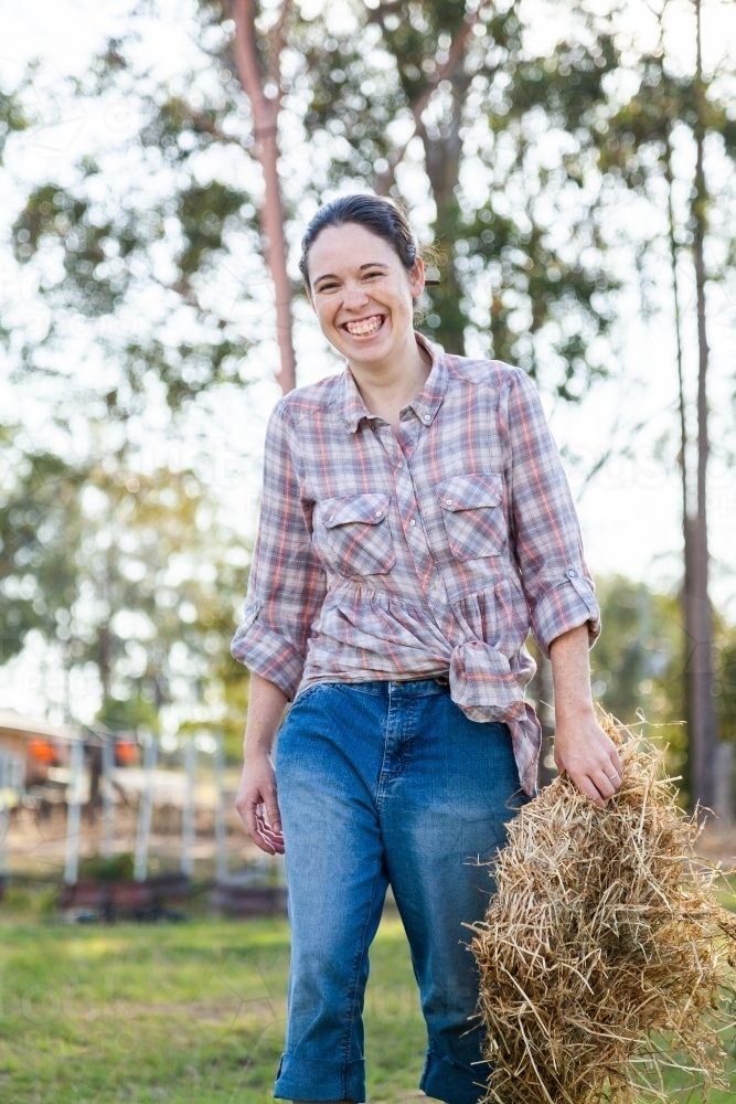 Young adult carrying hay biscuit to feed animals - Australian Stock Image
