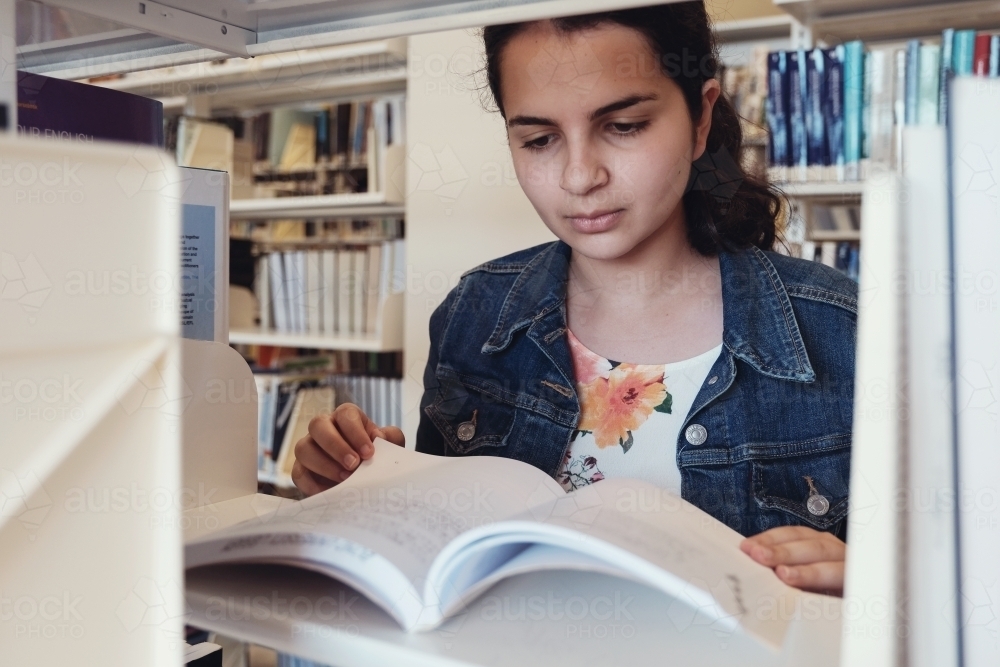 Young adult student reading in university library - Australian Stock Image