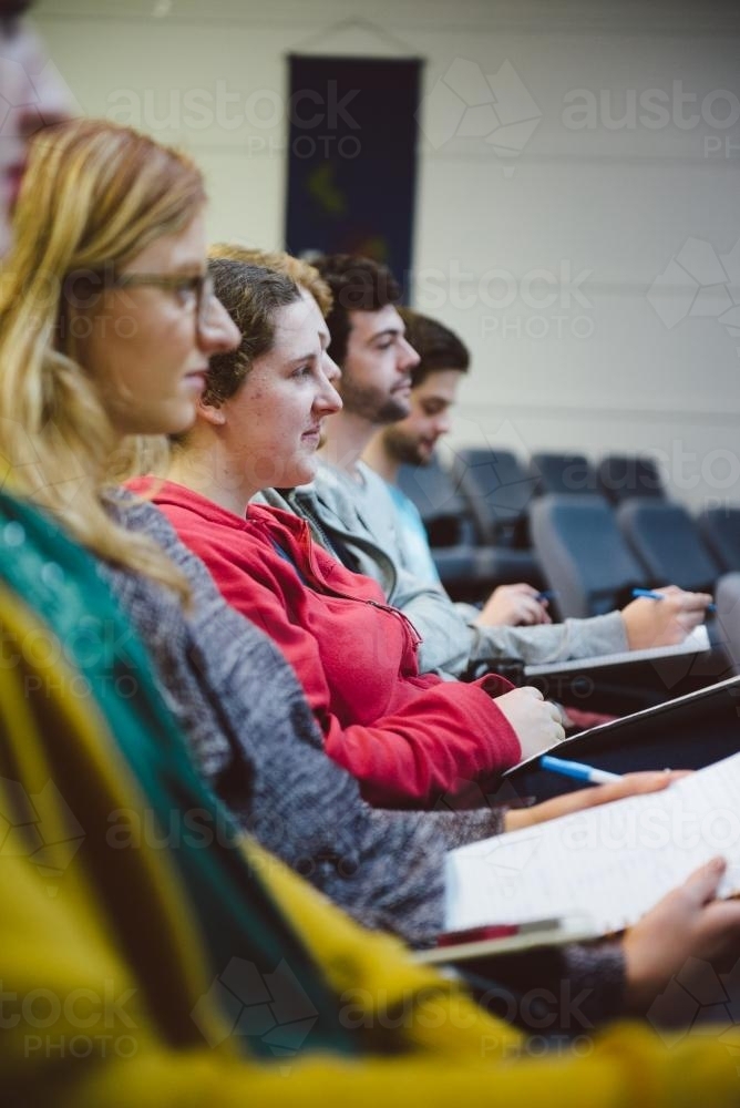 Young adult students listening to professor a university lecture hall - Australian Stock Image