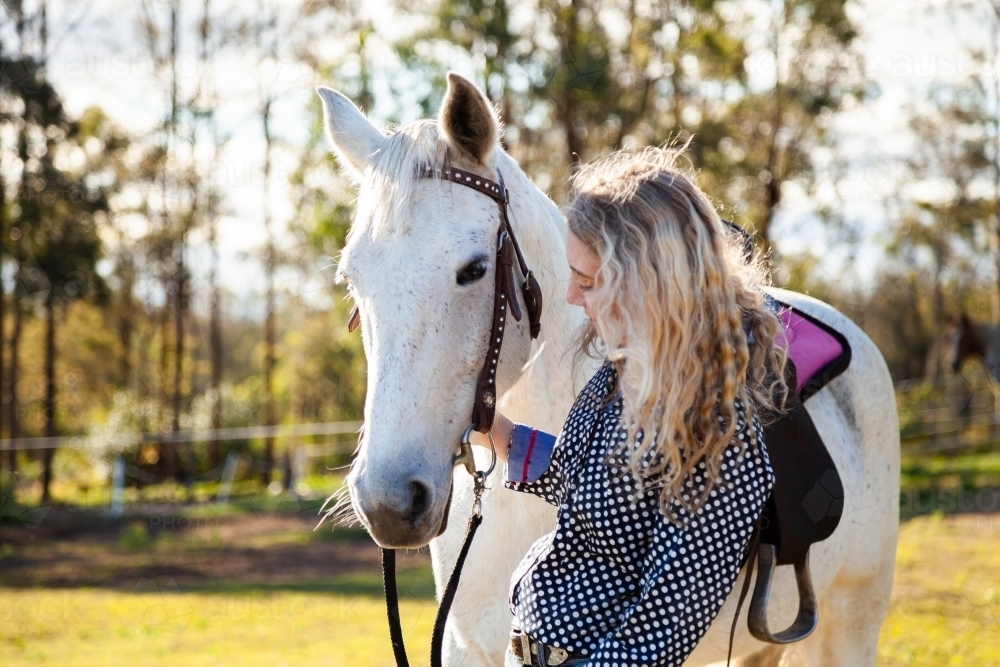Young adult talking to her horse in paddock - Australian Stock Image