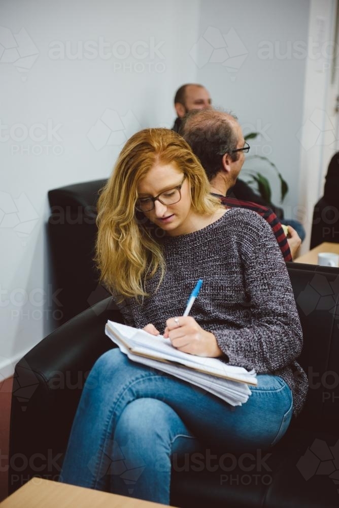 Young adult with glasses writing notes at university - Australian Stock Image