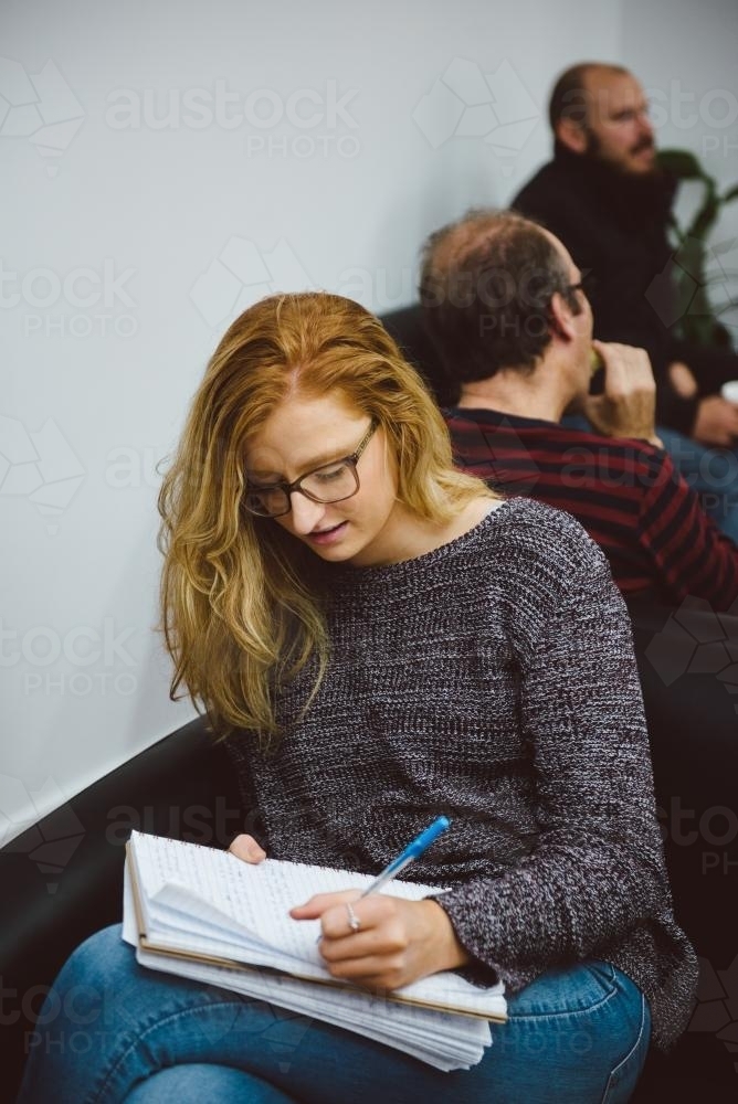 Young adult with glasses writing notes at university - Australian Stock Image