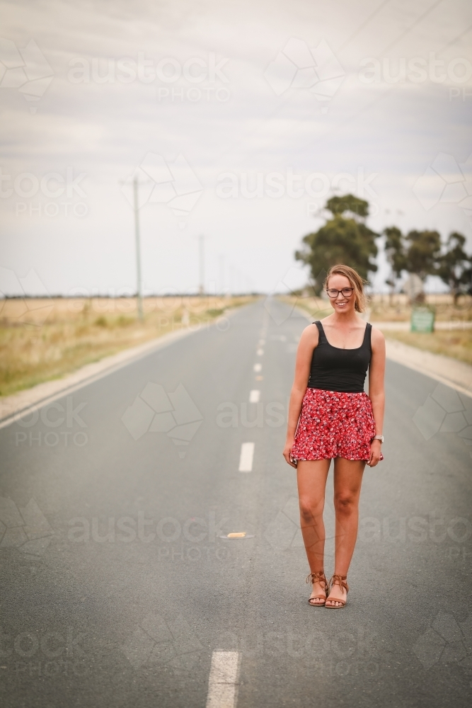 Young adult woman down empty rural road - Australian Stock Image