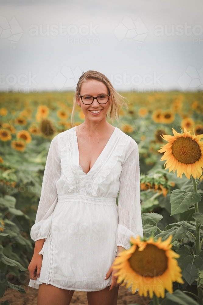 Image of Young adult woman standing in sunflower field - Austockphoto