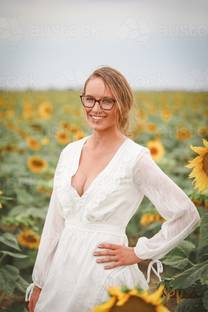Image of Young adult woman standing in sunflower field - Austockphoto