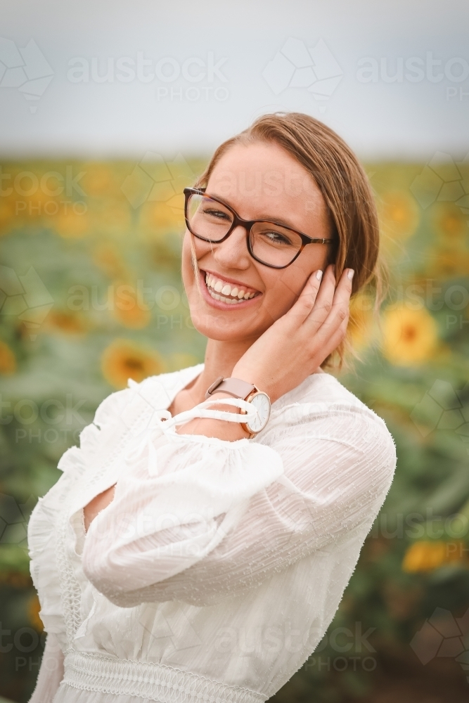 Young adult woman standing in sunflower field - Australian Stock Image