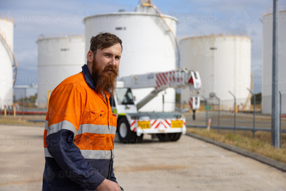 Young adult worker in high visibility clothes standing in an open concrete field. - Australian Stock Image