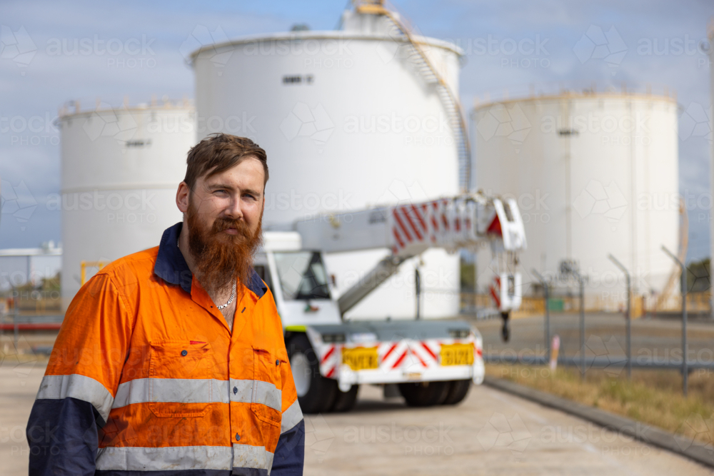 Young adult worker in high visibility clothes standing in an open concrete field. - Australian Stock Image