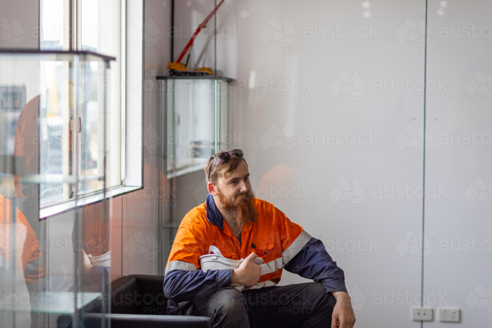 Young adult worker sitting on the couch inside the office. - Australian Stock Image