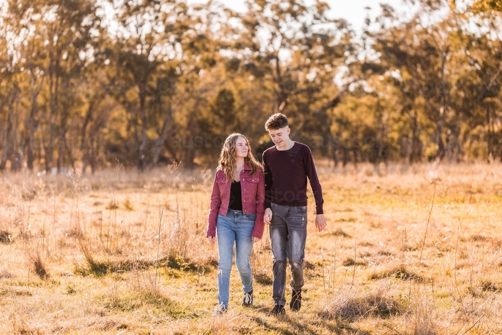 Young adults walking in open paddock talking - Australian Stock Image