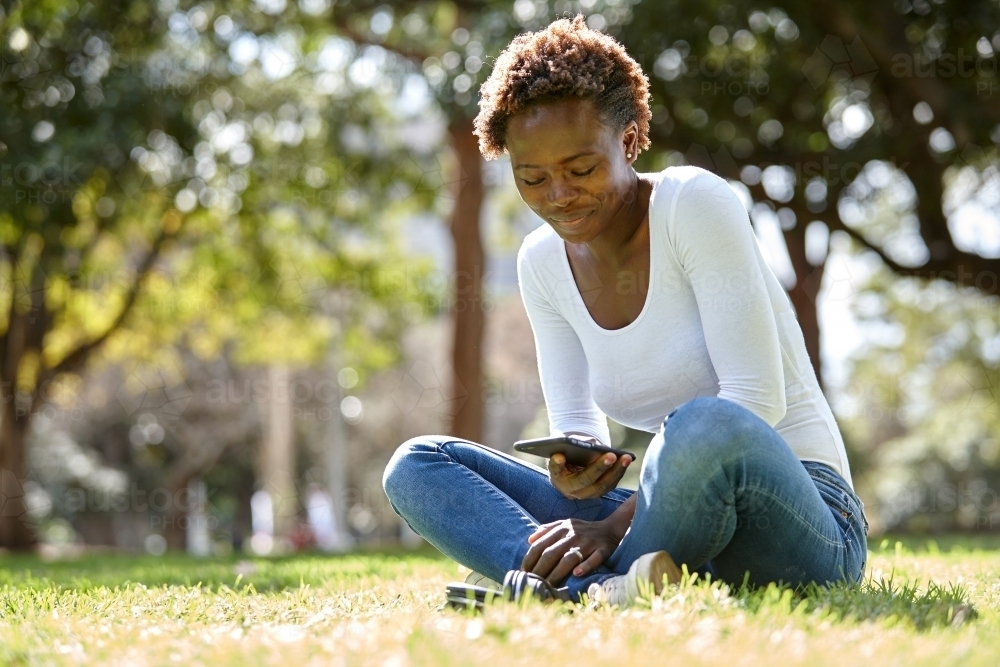 Young African woman smiling at park in sunshine - Australian Stock Image