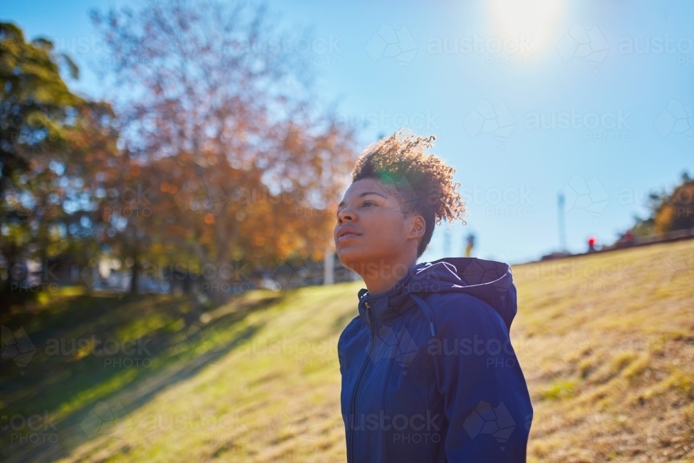 Young African woman standing on hillside in sun wearing activewear clothing - Australian Stock Image