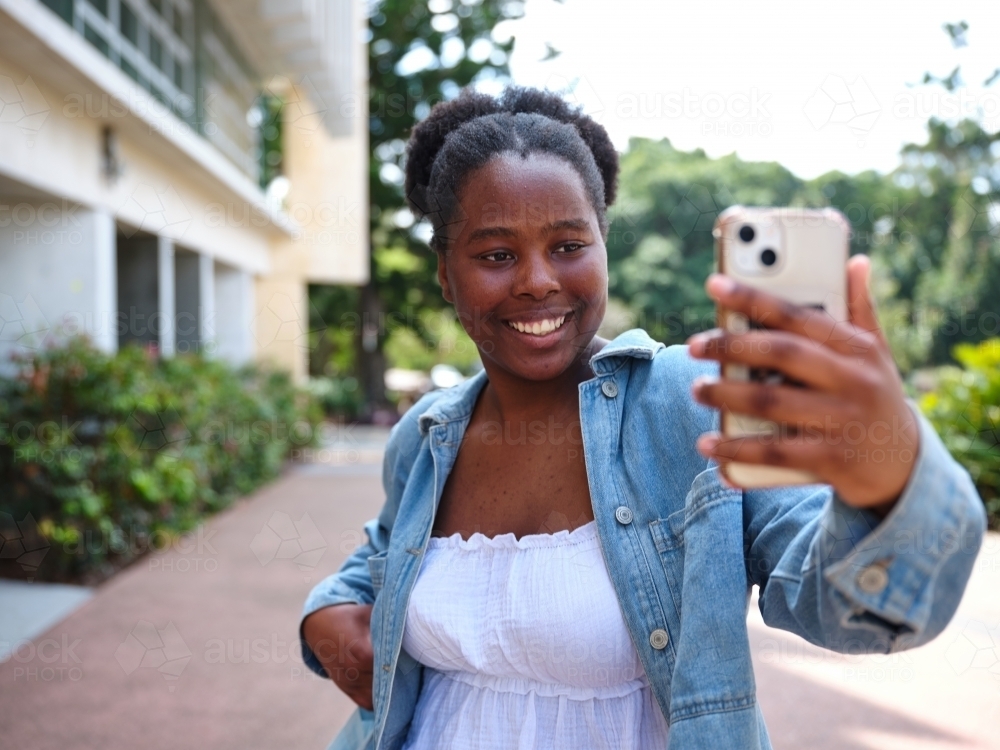 Young African woman taking a selfie on a university campus - Australian Stock Image