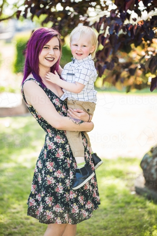 Young alternative mum holding young child smiling - Australian Stock Image