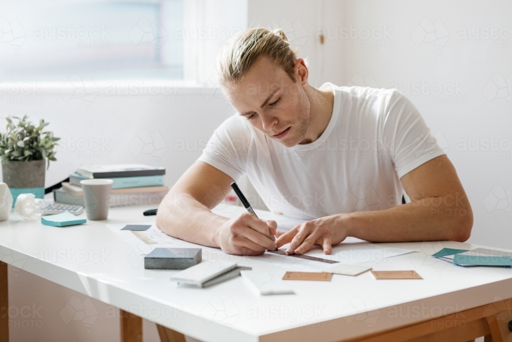 Young architect guy working on drawings in an office - Australian Stock Image