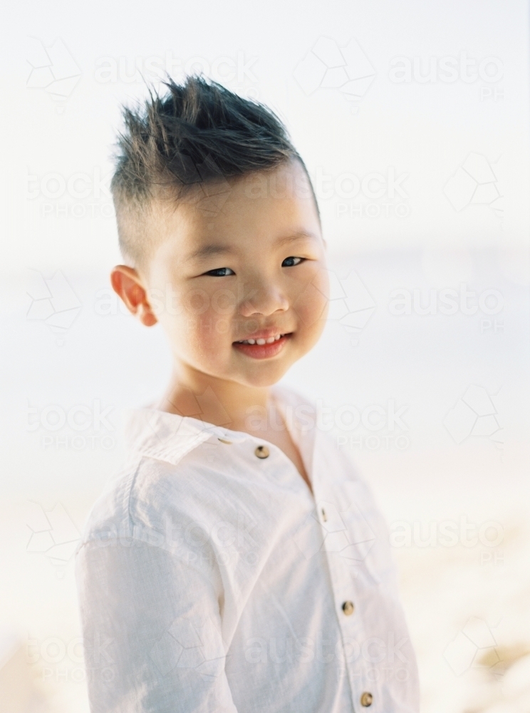 Young Asian boy outside, smiling at the camera - Australian Stock Image